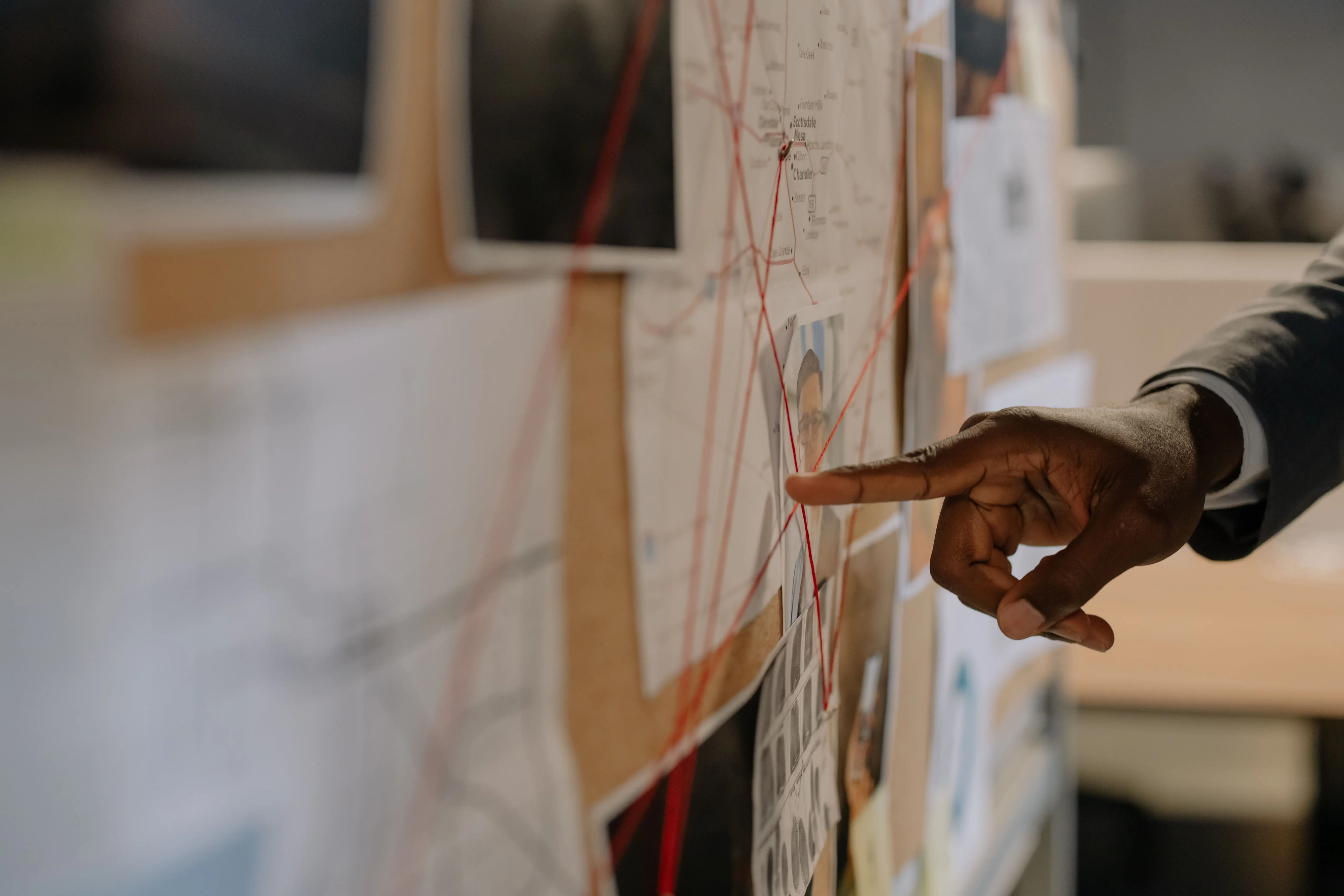 Investigator pointing at an evidence board with photographs and red thread connections