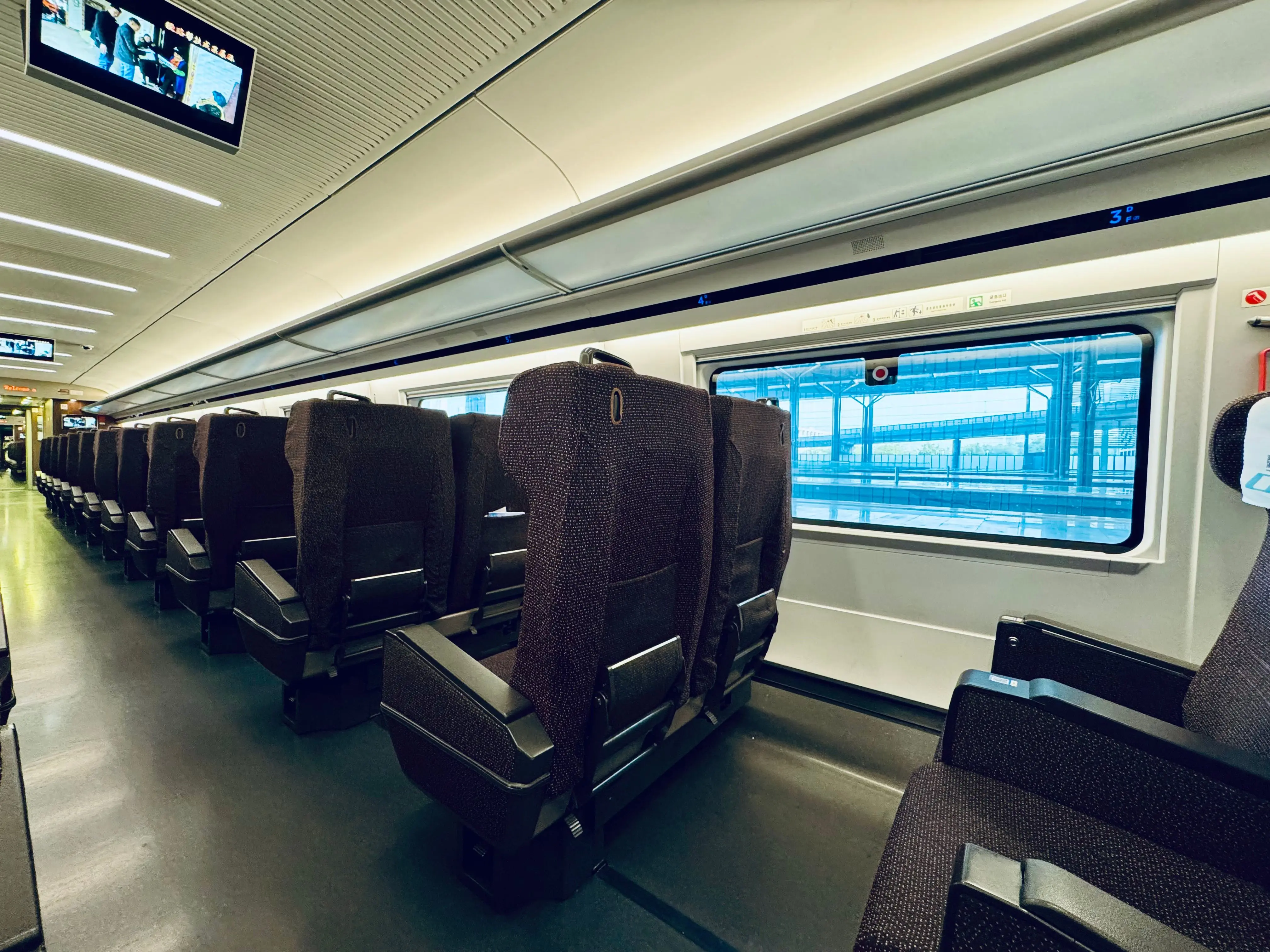 Train carriage interior showing onboard camera monitor and passenger seating